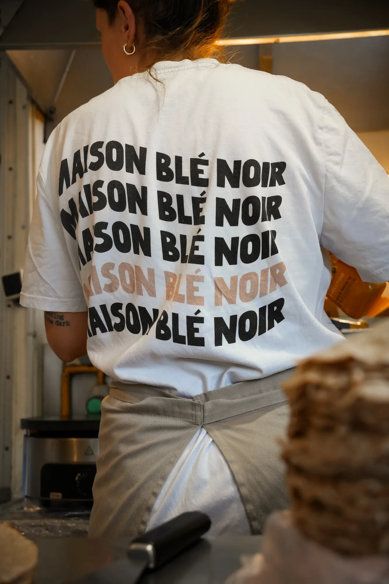 Crêpière de dos, tee-shirt à l'enseigne de la maison